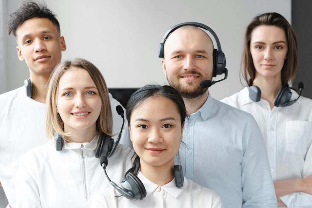 Diverse group of call center agents wearing headsets, smiling at the camera.